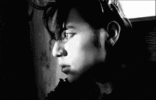 a black and white photo of a man 's face in a dark room .