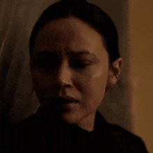 a close up of a woman 's face with a tear running down her cheek in a dark room .