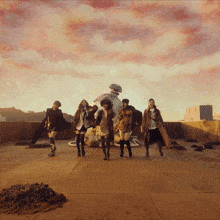 a group of women are dancing on a rooftop in front of a statue