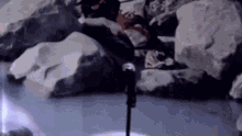 a person is standing in front of a microphone in a rocky area .