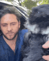 a man with a beard is holding a small black and white dog