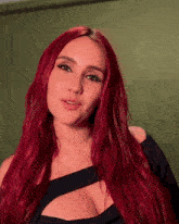 a woman with red hair and a black dress looks at the camera