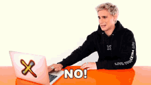 a man wearing a black hoodie that says live your extra life sits in front of a laptop computer