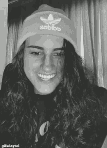 a woman wearing an adidas beanie is smiling