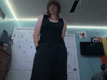 a woman wearing a black tank top and black pants stands in a room