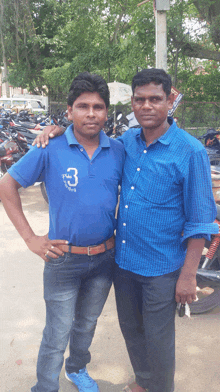 a man wearing a blue shirt with the number 3 on it poses with another man