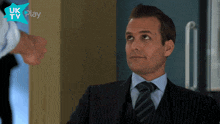 a man in a suit and tie is looking up at something in front of a sign that says uk tv play
