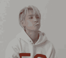 a young man wearing a white hoodie with a red letter t on it