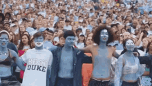 a group of people with blue paint on their faces and a shirt that says beat duke
