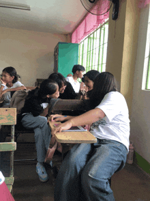 a girl wearing a white shirt that says ' i love you ' on it sits next to another girl in a classroom
