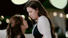 two women are standing next to each other and kissing each other .