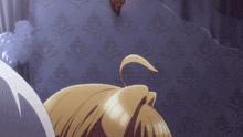 a person with blonde hair is laying on a bed with a patterned wall behind them