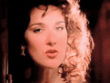 a close up of a woman 's face with curly hair making a funny face .