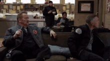 a group of men sit on a couch with a pillow that says " mother 's spot "