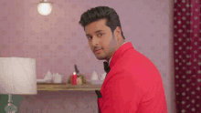 a man in a red suit and black bow tie is looking at the camera