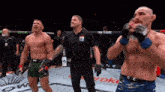 a referee stands between two fighters in a boxing ring