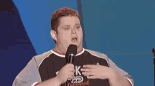 a man holding a microphone wearing a shirt that says k on it