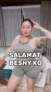 a woman with a shaved head is wearing shorts and a tank top that says " salamat beshy ko " on it