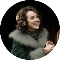 a woman wearing a green fur coat is smiling