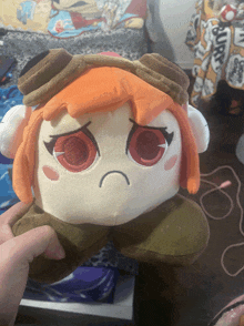 a person is holding a stuffed animal with an angry face