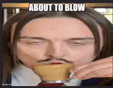 a man with a mustache is drinking from a cup with a caption that says about to blow .