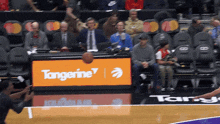 a basketball is being thrown in front of a sign for tangerine