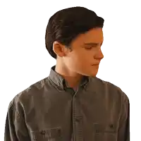 a young man in a denim shirt looks to his left