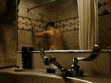 a man taking a shower in a bathroom with a native american pattern on the wall