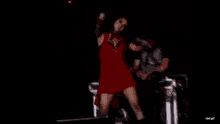 a woman in a red dress is dancing on a stage with a microphone .