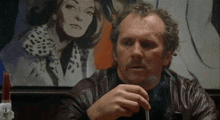 a man smoking a cigarette in front of a painting