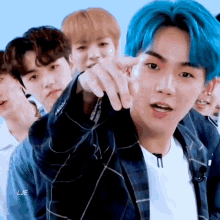 a group of young men with blue hair are standing next to each other pointing at the camera .