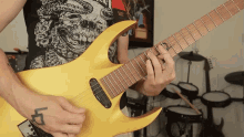a man with a tattoo on his left hand is playing a yellow electric guitar