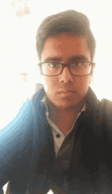 a man wearing glasses and a black jacket looks at the camera