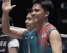 a man wearing a jersey with the malaysian flag on it waves his hand