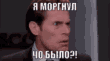 a man in a suit and tie is making a funny face with a foreign language caption .