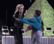 a woman in a blue jacket is dancing with a man in a blue shirt