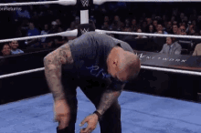 a wrestler is kneeling down in a wrestling ring while the crowd watches .