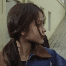 a close up of a woman 's face wearing a blue jacket with a brown collar