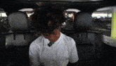 a young man with curly hair is sitting in the back seat of a car