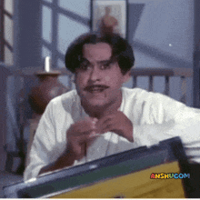 a man with a mustache is looking at himself in a mirror with anshu.com written on the bottom