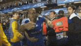 a man wearing a blue samsung shirt is surrounded by other people