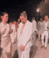 a woman in a white suit is standing next to a man in a suit .