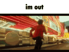 a man in a red jacket is running down a street in front of a neon sign that says im out .