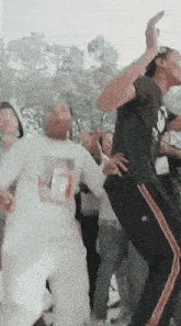 a group of people are dancing and one of them is wearing a white shirt with a picture of a girl on it