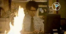 a man in a plaid shirt and tie is sitting at a desk with flames coming out of his head