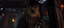 chewbacca from star wars is standing in a dark room looking out a window .