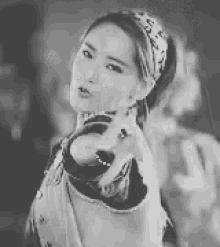 a black and white photo of a woman wearing a headband and pointing .