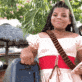 a woman is holding a blue suitcase and a cell phone .