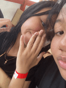 a girl with a red bracelet on her wrist covering her face with her hand