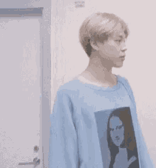 a young man wearing a blue sweater with a picture of mona lisa on it